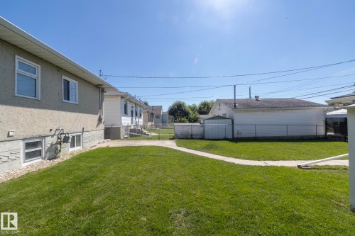 Expansive grassy yard with a concrete pathway and stucco exterior - 12322 94 Street Nw, Edmonton, AB - Outdoor