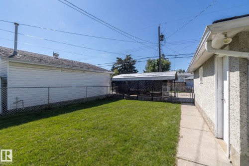 Expansive grassy area with concrete pathway, chain-link fencing, and covered structure - 12322 94 Street Nw, Edmonton, AB - Outdoor With Exterior
