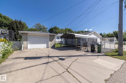 Detached garage with a white overhead door, concrete driveway, and a chain-link fence - 12322 94 Street Nw, Edmonton, AB - Outdoor