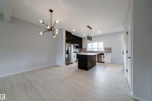 Open concept living space featuring light wood-finish flooring, a modern chandelier, and recessed lighting - 7109 Chivers Close Sw, Edmonton, AB - Indoor Photo Showing Kitchen