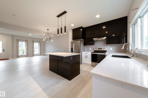 Contemporary kitchen with glossy black cabinetry, light-toned countertops, and stainless steel appliances - 7109 Chivers Close Sw, Edmonton, AB - Indoor Photo Showing Kitchen With Stainless Steel Kitchen With Upgraded Kitchen