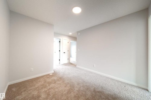 Neutral wall paint, textured carpet, white trim, recessed lighting, and panel doors with dark hardware - 7109 Chivers Close Sw, Edmonton, AB - Indoor Photo Showing Other Room