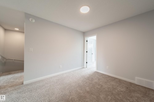 Carpeted flooring, light grey wall paint, recessed ceiling lighting, white trim, and a white interior door - 7109 Chivers Close Sw, Edmonton, AB - Indoor Photo Showing Other Room