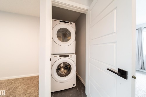Stackable washer and dryer appliances within a dedicated closet - 7109 Chivers Close Sw, Edmonton, AB - Indoor Photo Showing Laundry Room