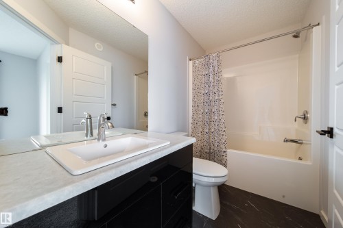 White countertop with an undermount sink, chrome faucet, and integrated mirror - 7109 Chivers Close Sw, Edmonton, AB - Indoor Photo Showing Bathroom