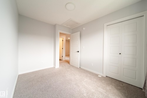 Light gray wall finishes, gray carpeting, white bi-fold closet doors, white interior door, and a flush mount ceiling light - 7109 Chivers Close Sw, Edmonton, AB - Indoor Photo Showing Other Room