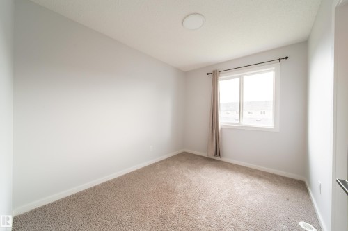 Neutral paint palette, carpeted flooring, window with white trim, and a ceiling-mounted light fixture - 7109 Chivers Close Sw, Edmonton, AB - Indoor Photo Showing Other Room