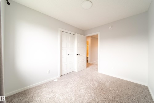Plush carpet flooring, neutral paint palette, flush-mount ceiling light, and panel doors - 7109 Chivers Close Sw, Edmonton, AB - Indoor Photo Showing Other Room