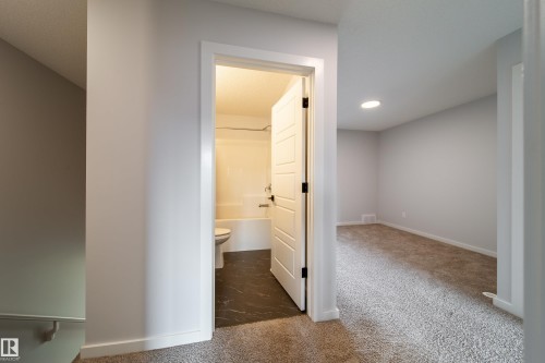 Carpeted flooring, recessed lighting, white interior doors, and a full bathroom with dark-toned flooring - 7109 Chivers Close Sw, Edmonton, AB - Indoor Photo Showing Other Room