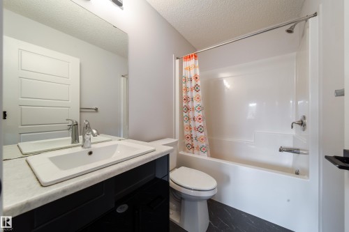 White paneled door, a single vanity with a white basin sink, polished chrome faucet, and a large wall-mounted mirror - 7109 Chivers Close Sw, Edmonton, AB - Indoor Photo Showing Bathroom