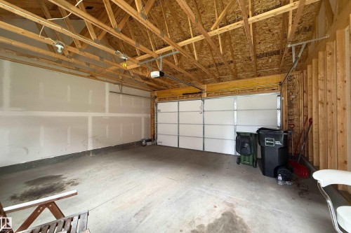 Exposed wood framing and ceiling, concrete flooring, and an overhead garage door - 7109 Chivers Close Sw, Edmonton, AB - Indoor Photo Showing Garage