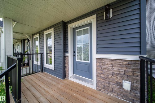 Covered front porch featuring wood-finish decking and black railings - 7109 Chivers Close Sw, Edmonton, AB - Outdoor With Deck Patio Veranda With Exterior