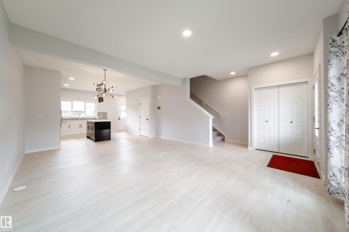 Open-concept layout with wood-finish flooring, recessed lighting, a modern chandelier, and a kitchen island with storage - 7109 Chivers Close Sw, Edmonton, AB - Indoor Photo Showing Other Room