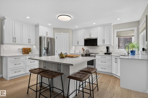 White shaker-style cabinetry, stainless steel appliances, light wood-finish flooring, recessed lighting, and a kitchen island with seating - 30 Hillcrest Place, St. Albert, AB - Indoor Photo Showing Kitchen With Stainless Steel Kitchen With Upgraded Kitchen
