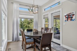 Expansive window wall with transom, glass-paned exterior door, wood-finish flooring, and a modern chandelier - 