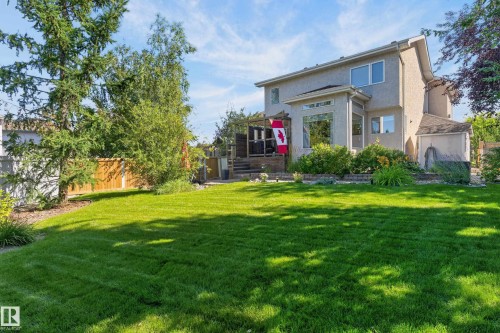 Expansive backyard featuring a manicured lawn, mature trees, and a multi-level deck with wood railing - 30 Hillcrest Place, St. Albert, AB - Outdoor