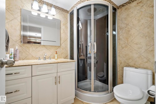Bathroom featuring a white vanity with granite-style countertop, a chrome faucet, and a large wall-mounted mirror - #25 3811 85 St Nw, Edmonton, AB - Indoor Photo Showing Bathroom