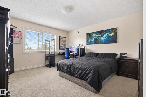 Wall-to-wall carpeting with a large window and white trim - #25 3811 85 St Nw, Edmonton, AB - Indoor Photo Showing Bedroom