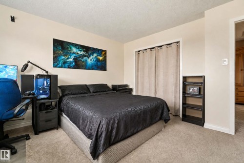 Spacious bedroom with neutral carpeting, black upholstered bed frame, and soft ambient lighting - #25 3811 85 St Nw, Edmonton, AB - Indoor Photo Showing Bedroom