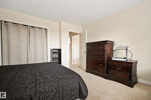 Neutral tone wall color, textured ceiling, carpeted flooring, and a doorway opening to an interior space - #25 3811 85 St Nw, Edmonton, AB - Indoor Photo Showing Bedroom