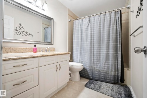 White shaker-style vanity with ample storage, a light-toned countertop, and a framed mirror - #25 3811 85 St Nw, Edmonton, AB - Indoor Photo Showing Bathroom