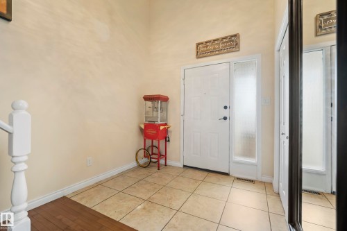 Entryway featuring a panel door with a sidelight, ceramic tile flooring, and a partial wood-finish floor section - #25 3811 85 St Nw, Edmonton, AB - Indoor Photo Showing Other Room