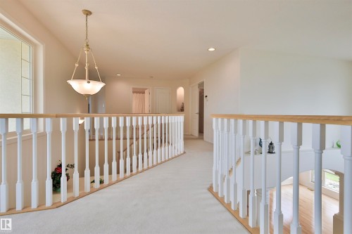 Second-story landing featuring a decorative chandelier, recessed lighting, and white spindle railing with a wood-finish top rail - 237 Darlington Crescent Nw, Edmonton, AB - Indoor Photo Showing Other Room