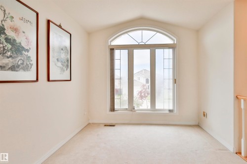Arched window with transom details, neutral wall paint, and light-colored carpeting - 237 Darlington Crescent Nw, Edmonton, AB - Indoor Photo Showing Other Room
