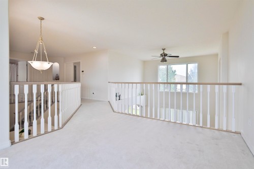 White baluster railing with light wood-finish top rail, soft carpet flooring, and a ceiling fan with integrated lighting - 237 Darlington Crescent Nw, Edmonton, AB - Indoor Photo Showing Other Room