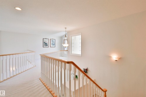 Carpeted upper hallway featuring a wood and white spindle railing, recessed ceiling lighting, a pendant light fixture, and a window with divided lites - 237 Darlington Crescent Nw, Edmonton, AB - Indoor Photo Showing Other Room