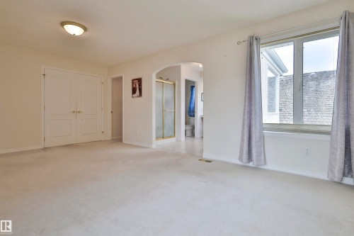 Wall-to-wall carpeting, double closet doors, archway entry, and large window with trim - 237 Darlington Crescent Nw, Edmonton, AB - Indoor Photo Showing Other Room