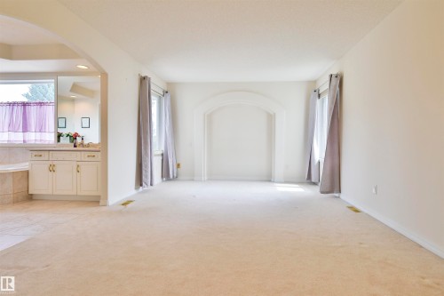 Carpeted flooring throughout, arched alcove, and multiple windows with drapery - 237 Darlington Crescent Nw, Edmonton, AB - Indoor Photo Showing Other Room