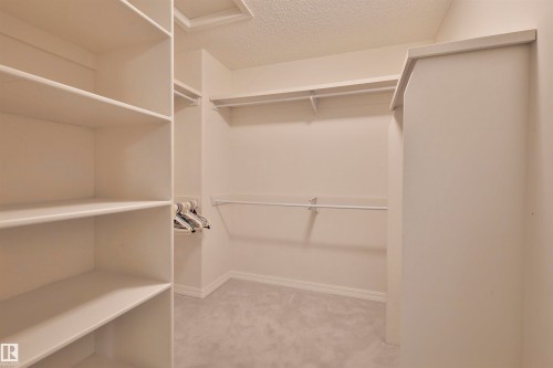 Walk-in closet featuring built-in shelving, white walls, and carpet flooring - 237 Darlington Crescent Nw, Edmonton, AB - Indoor With Storage