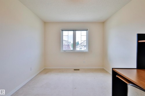 Single window with white trim, light-colored carpeting, and a built-in desk unit with wood-finish top and black shelving - 237 Darlington Crescent Nw, Edmonton, AB - Indoor Photo Showing Other Room