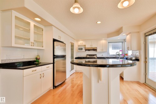 Kitchen featuring light wood-finish flooring, white cabinetry, dark countertops, and stainless steel appliances - 237 Darlington Crescent Nw, Edmonton, AB - Indoor Photo Showing Kitchen