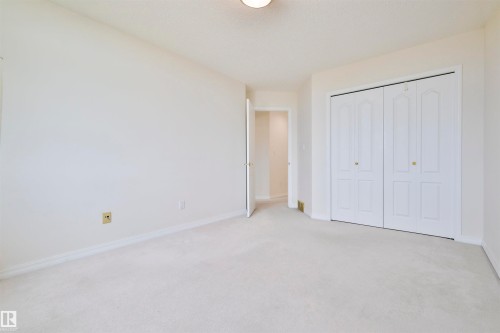 Carpeted flooring with light-toned walls, featuring a ceiling-mounted light fixture and bi-fold closet doors - 237 Darlington Crescent Nw, Edmonton, AB - Indoor