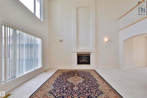 Two-story ceiling, large windows with vertical blinds, fireplace with mantel, upper-level railing, arched doorway - 237 Darlington Crescent Nw, Edmonton, AB - Indoor Photo Showing Other Room With Fireplace