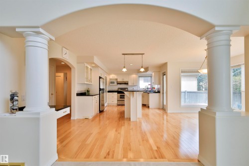 Architectural columns with archway detail, light wood-finish flooring, white cabinetry, stainless steel appliances, and dark countertops - 237 Darlington Crescent Nw, Edmonton, AB - Indoor