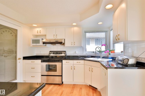 White cabinetry with gold-tone hardware, dark countertops, stainless steel appliances, and a built-in kitchen sink - 237 Darlington Crescent Nw, Edmonton, AB - Indoor Photo Showing Kitchen With Double Sink