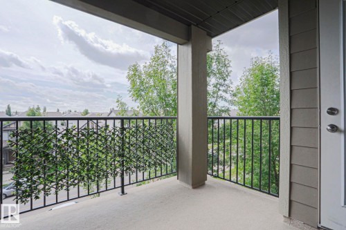 Balcony with concrete flooring, black metal railing, and a privacy screen - #321 270 Mcconachie Dr Nw, Edmonton, AB - Outdoor With Balcony With Exterior