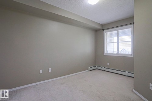 Light gray wall paint, carpeting, window with horizontal blinds, baseboard heating, and a flush mount ceiling light fixture - #321 270 Mcconachie Dr Nw, Edmonton, AB - Indoor Photo Showing Other Room