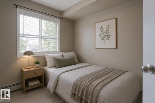 Window with white blinds, wood-finish nightstand with drawer, neutral wall color, and carpeted flooring - #321 270 Mcconachie Dr Nw, Edmonton, AB - Indoor Photo Showing Bedroom