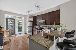Kitchen featuring wood-finish flooring, dark wood cabinetry, stainless steel appliances, and granite countertops with a breakfast bar - 
