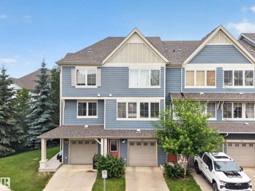 Three-story townhouse featuring blue horizontal siding with white trim, a gabled roofline, and attached garages - #53 603 Watt Bv Sw, Edmonton, AB - Outdoor With Facade