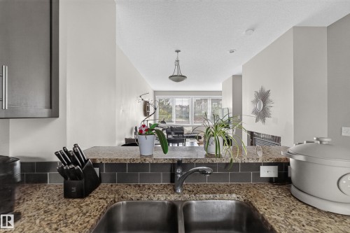 Kitchen sink with a double basin, granite-style countertop, and a dark subway tile backsplash - #53 603 Watt Bv Sw, Edmonton, AB - Indoor Photo Showing Kitchen With Double Sink