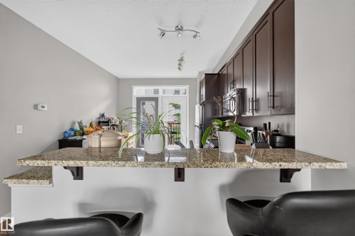 Kitchen breakfast bar featuring a granite countertop with integrated shelving - #53 603 Watt Bv Sw, Edmonton, AB - Indoor Photo Showing Kitchen With Upgraded Kitchen