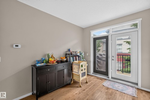 Outdoor access from glass-paneled door, complemented by wood-finish flooring and neutral wall tones - #53 603 Watt Bv Sw, Edmonton, AB - Indoor Photo Showing Other Room