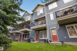 Multi-level townhome exterior featuring blue siding, white trim, and red entry doors - 