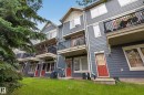 Multi-level townhome exterior featuring blue siding, white trim, and red entry doors - #53 603 Watt Bv Sw, Edmonton, AB  - Outdoor With Balcony 