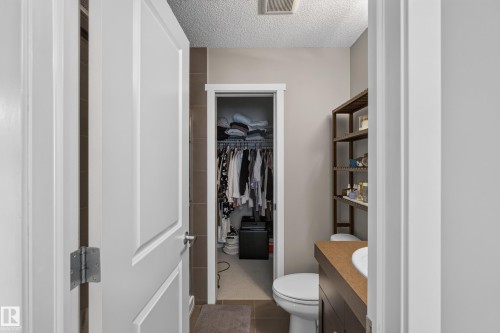 Bathroom featuring a single vanity with an integrated sink, a built-in toilet, and open shelving - #53 603 Watt Bv Sw, Edmonton, AB - Indoor Photo Showing Bathroom